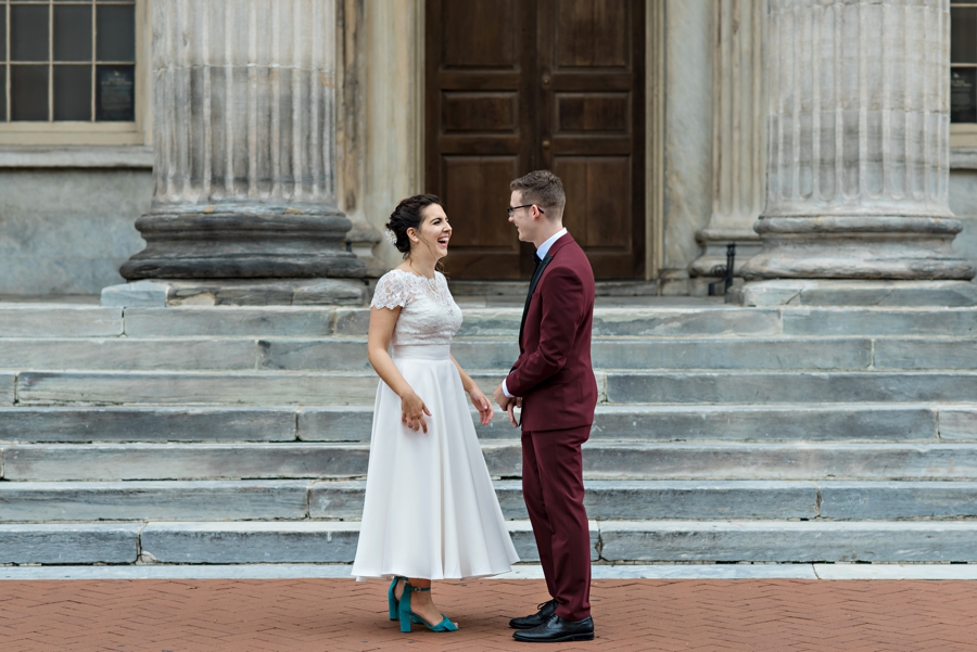 A bride and groom hold hands in front of a historic building in Philadelphia.
